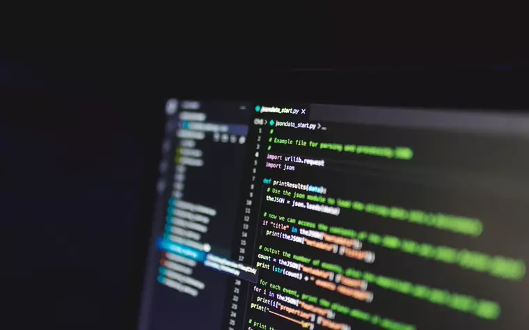 Pantalla de computadora mostrando líneas de código en un cuarto oscuro